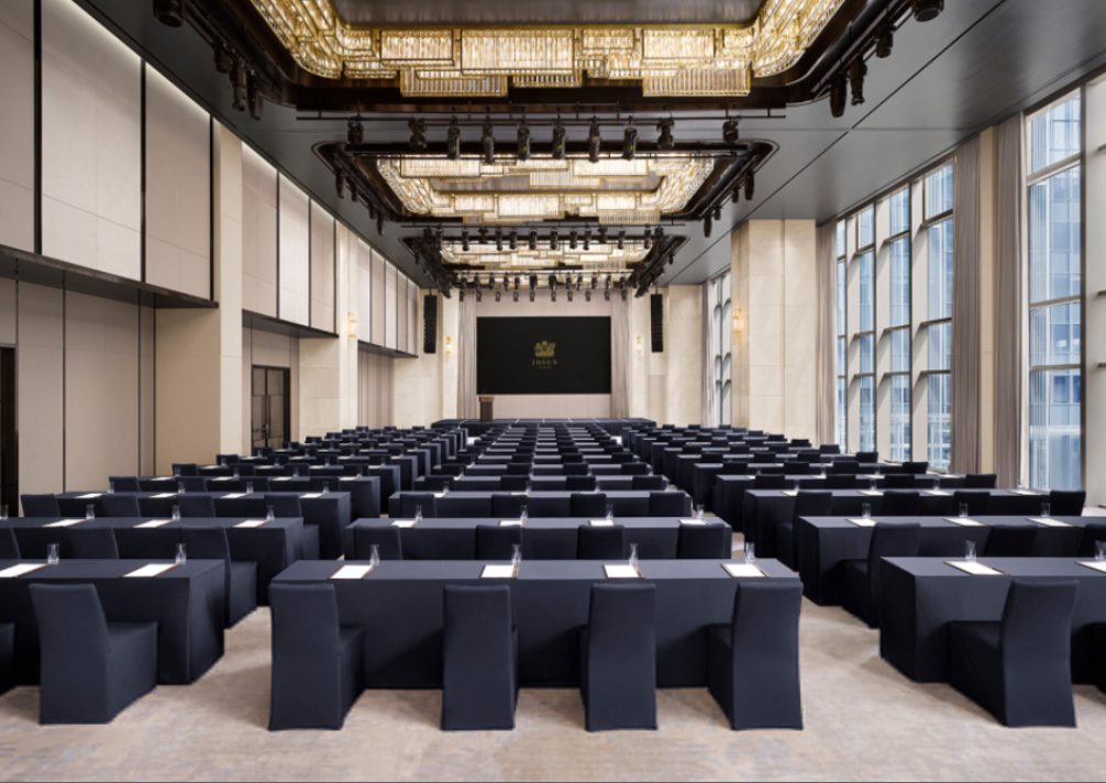 Modern conference hall with elegant lighting, dark seating, and large windows
