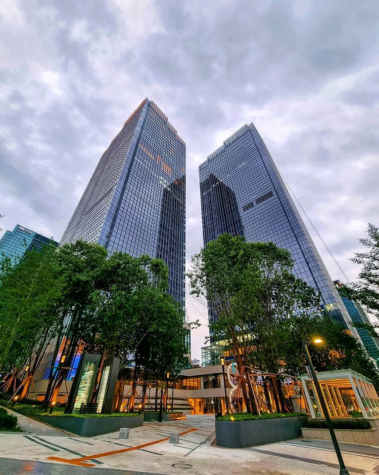 Modern glass skyscrapers with landscaped plaza and greenery